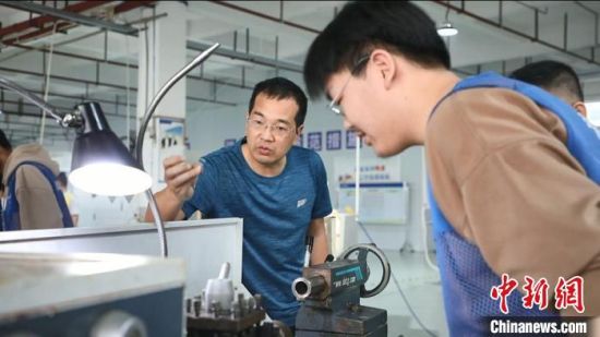 新田县职业中专机械加工专业学生在老师指导下完成机器调试、材料打磨等工序。　肖亚湘 摄